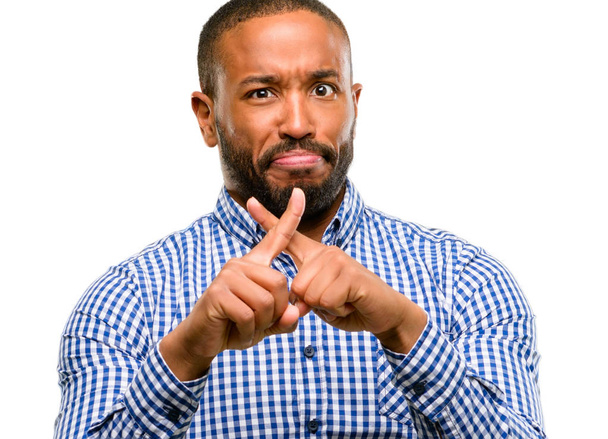Hombre afroamericano con barba molesto con mala actitud haciendo señal de stop con la mano, diciendo no, expresando seguridad, defensa o restricción, tal vez empujando aislado sobre fondo blanco
 - Foto, imagen