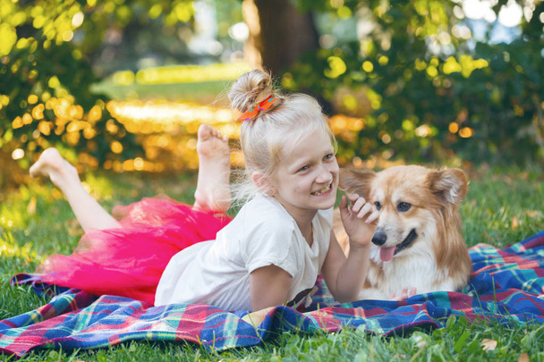 felices vacaciones divertidas - hermosa chica rubia y corgi esponjosa en el césped en un verano soleado da
 - Foto, Imagen