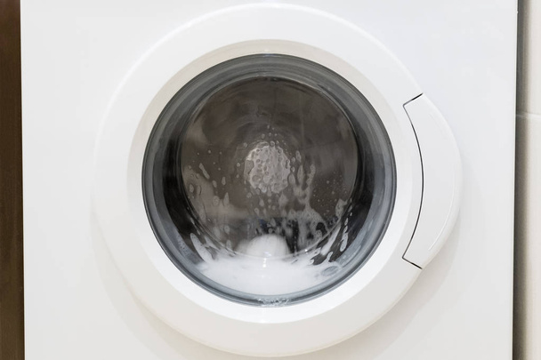 Wasmachinedeur met draaiende kledingstukken binnenin - Foto, afbeelding