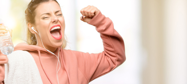 Jonge sport vrouw dragen van workout sweatshirt blij en opgewonden vieren overwinning groot succes, kracht, energie en positieve emoties te uiten. Nieuwe baan vreugdevolle viert - Foto, afbeelding