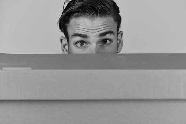 Man hiding behind cardboard box on grey background - Foto, immagini