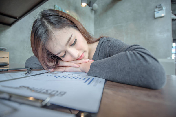 Νέοι ελκυστικού επιχειρηματικού ασιατική γυναίκα κοιμάται, κοιμάται ή λαμβάνοντας έναν υπνάκο στο γραφείο, κουρασμένος επιχειρήσεων γυναίκα λογιστής με τους λογαριασμούς και φακέλους χαρτί στο γραφείο, κουρασμένος νεαρή γυναίκα με φορητό υπολογιστή. - Φωτογραφία, εικόνα