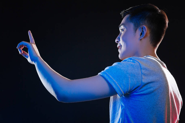 Positive Asian man looking at his finger - Фото, изображение