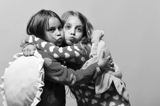 happy girls. Kids with funny faces make air kisses and hold pillows - Fotó, kép