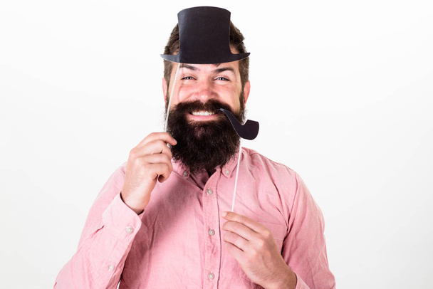 Man in pink shirt with stylish beard and mustache at party, Christmas concept. Bearded man holding paper top hat and smoking pipe. Gentleman with long beard and big smile isolated on white background - Foto, imagen