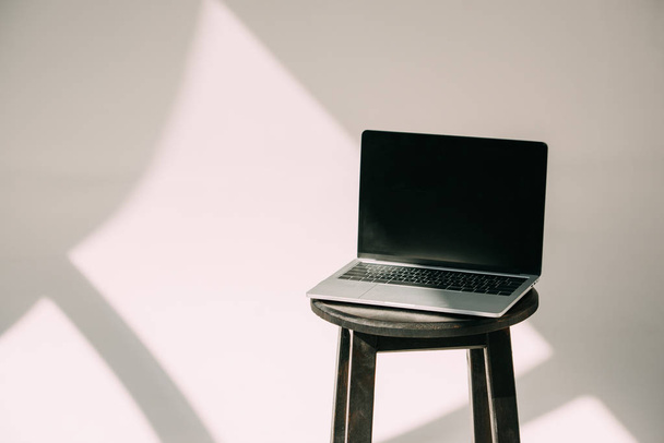 open laptop with black screen on stool on grey - Foto, imagen