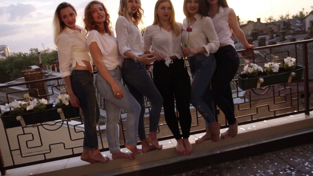 Sechs kaukasische Mädchen stehen auf einem Balkon und posieren für die Kamera. Freizeitkleidung. Nahaufnahme der Beine von Mädchen in Jeans. Hintergrund der alten Stadt - Filmmaterial, Video