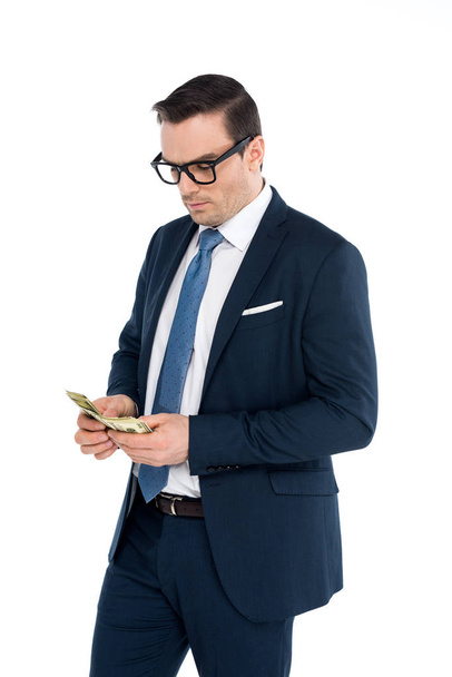 handsome businessman in eyeglasses counting dollar banknotes isolated on white - Foto, Imagen