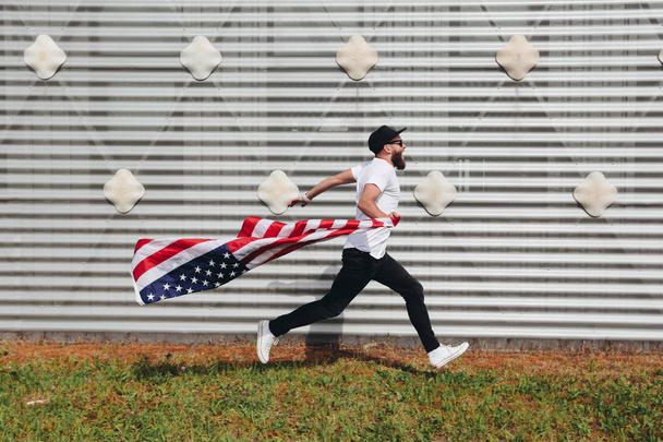Happy hipster man holding American or USA flag. He is wearing casual clothes. - Foto, immagini