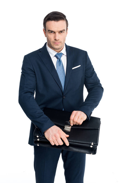 serious middle aged businessman holding briefcase and looking at camera isolated on white - Fotografie, Obrázek