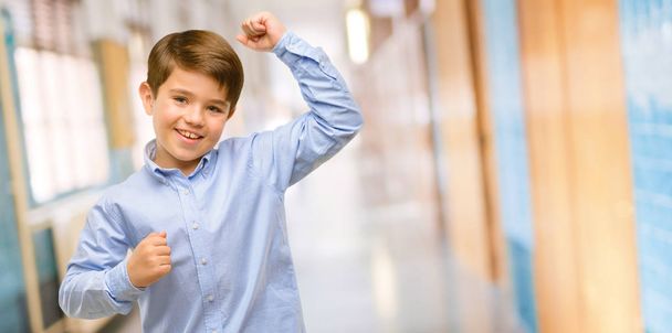 Niño guapo con ojos verdes feliz y emocionado expresando gesto ganador. Exitoso y celebrando la victoria, triunfante en el pasillo escolar
 - Foto, imagen