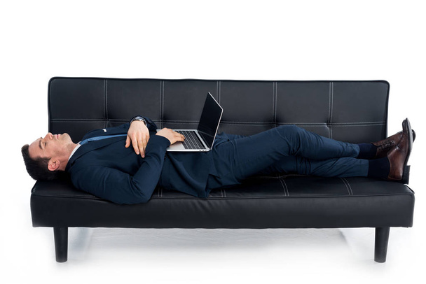 middle aged businessman lying on couch with laptop on white - Foto, afbeelding