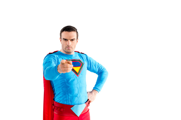confident male superhero standing with hand on waist and pointing at camera isolated on white  - Foto, afbeelding