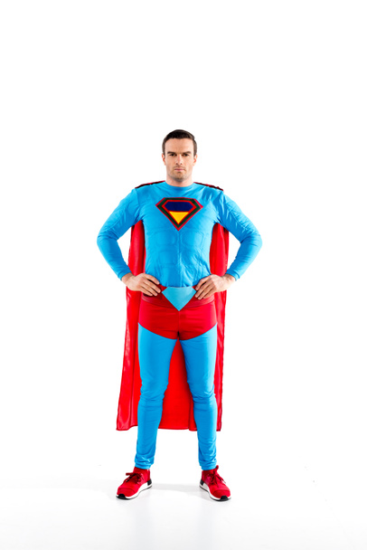 full length view of handsome mid adult superman standing with hands on waist and looking at camera isolated on white - Фото, изображение