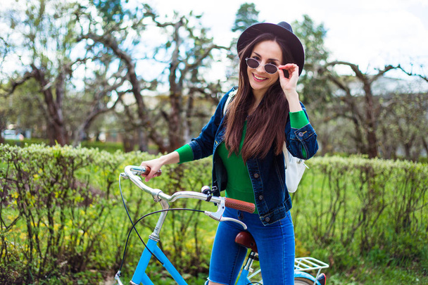 siyah şapkalı bisikletle poz genç kadın - Fotoğraf, Görsel