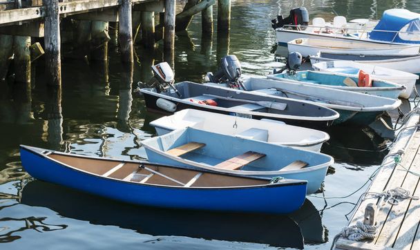 Motor and row boats are tied to a dock in Rocklport Maine on a sunny summer afternoon in August. - Photo, Image