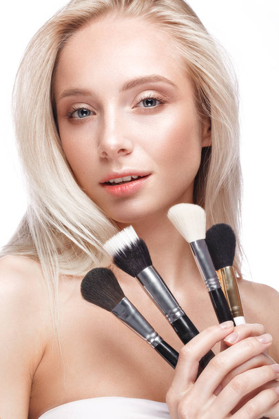 Beautiful young girl with a light natural make-up, brushes for cosmetics and nude manicure. Beauty face. - Fotó, kép