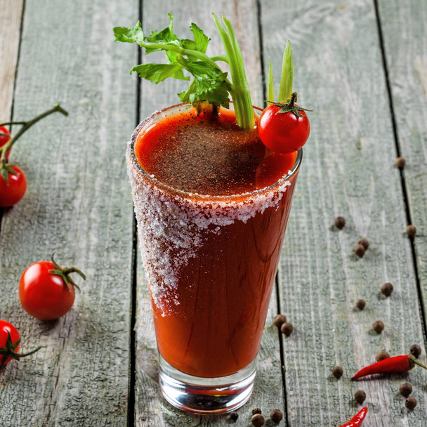 Classic bloody mary in a glass on a wooden table. Alcoholic drink made of tomato juice, vodka, pepper, salt, lemon juice, celery and other flavorings. Closeup shot. - Foto, afbeelding