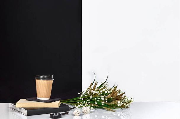 Flowers, book, notebook and cup of coffee, black and white wall. - Foto, imagen