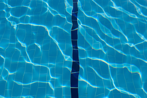 Water lens to pool bottom. Blue line in swimming pool. Sunlight on water in pool. Sun glare in swimming pool - Photo, Image