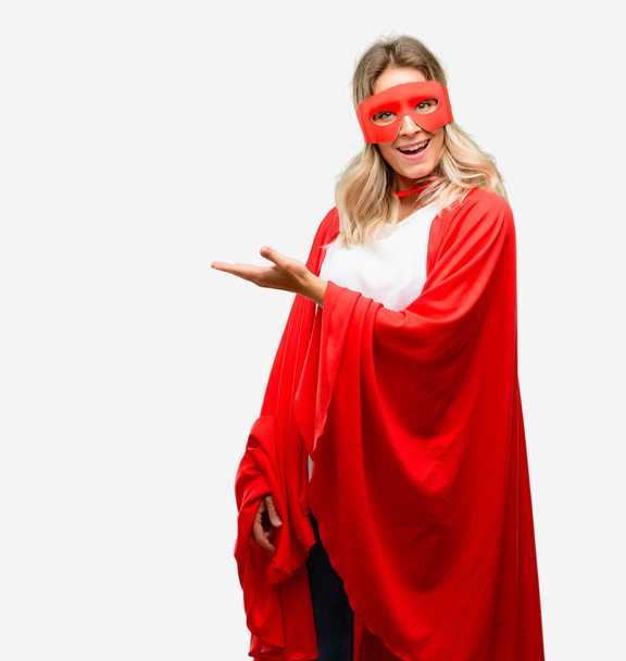 Young super hero woman wearing cape holding something in empty hand - Foto, Bild