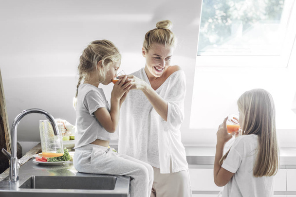 Two cute Caucasian girls sisters enjoying breakfast at home with their beautiful mother. - Foto, imagen