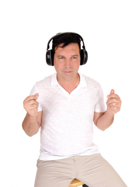 A good looking man sitting on a chair with his headphones on an - Foto, imagen