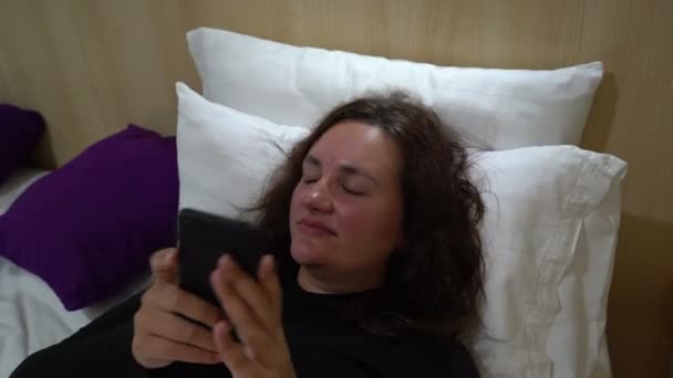 Young beautiful woman in bed turn off smartphone and go sleep - Кадри, відео