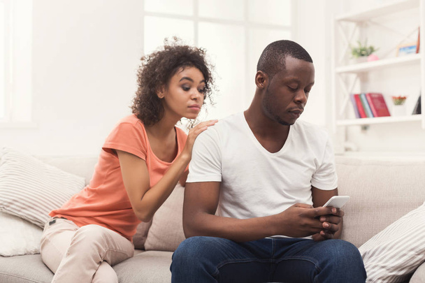 Couple afro-américain à la maison, homme textos
 - Photo, image