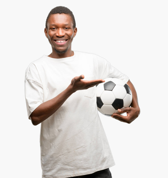 Africano nero uomo tenendo palla da calcio che tiene qualcosa in mano vuota
 - Foto, immagini