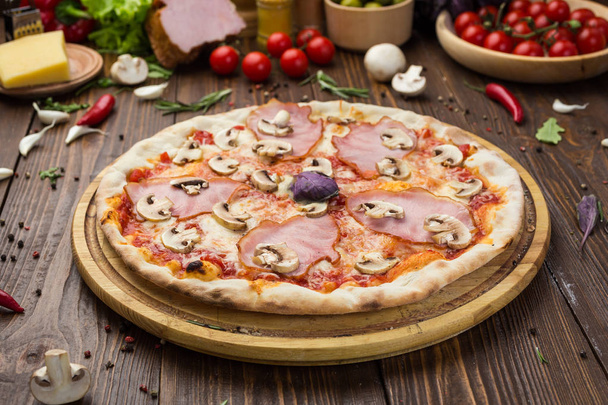 Deliziosa pizza italiana con prosciutto e funghi su sfondo di legno
 - Foto, immagini