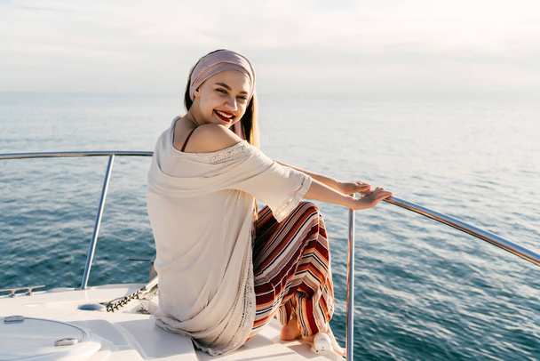 happy luxury girl in stylish summer clothes sits on her yacht, sails on the Caribbean sea - Foto, afbeelding