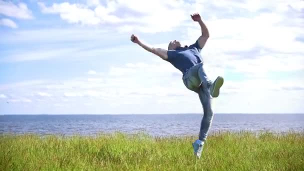 Genç adam arka plan nehir üstünde belgili tanımlık tepe üzerinde akrobatik stunts gerçekleştirir - Video, Çekim