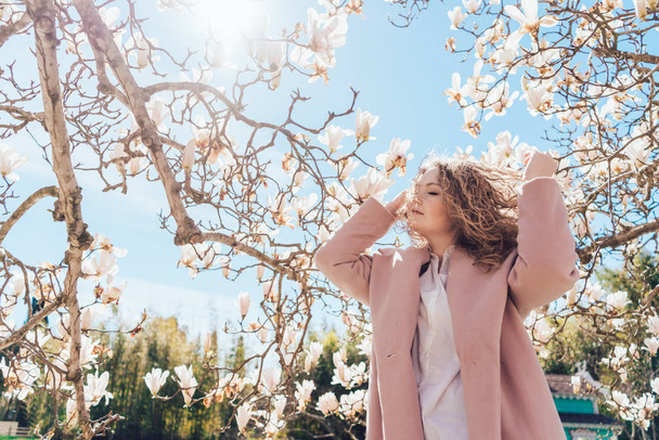 elegant curly woman enjoys the sun and warmth in the park, loves the spring - 写真・画像