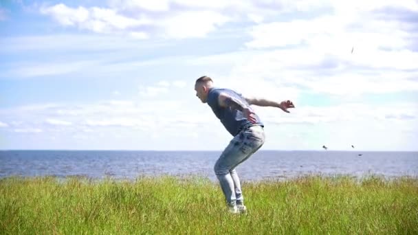 jovem acrobata masculino executa flip na colina sobre o rio no dia ensolarado
 - Filmagem, Vídeo