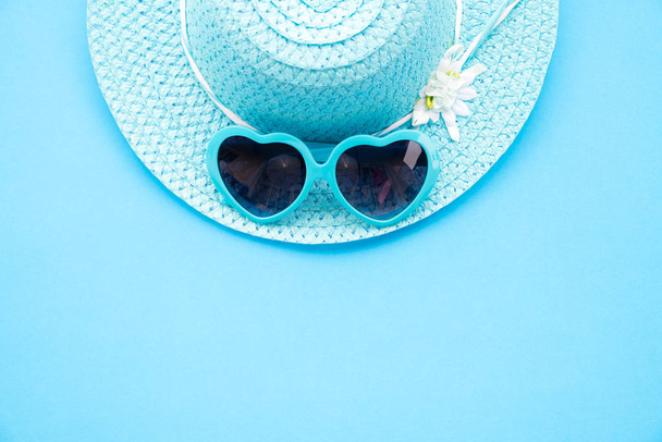 Accessori da spiaggia tra cui occhiali da sole blu e cappello da spiaggia ciano su sfondo di carta ciano per le vacanze estive e concetto di vacanza
. - Foto, immagini