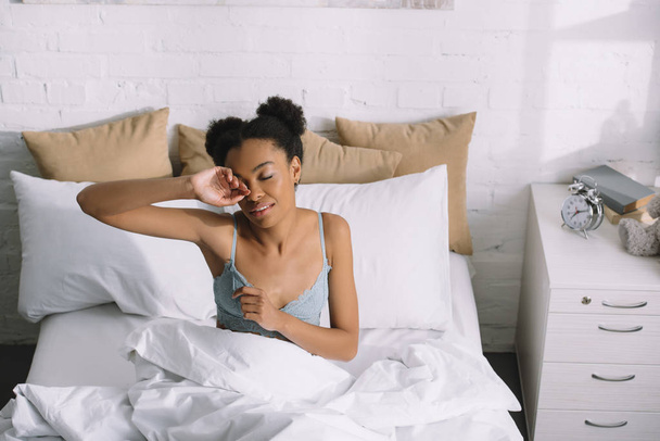young african american woman waking up in bedroom - Foto, afbeelding