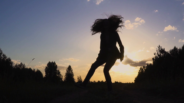 silhueta de jovem mulher pulando ao pôr do sol câmera lenta
 - Filmagem, Vídeo