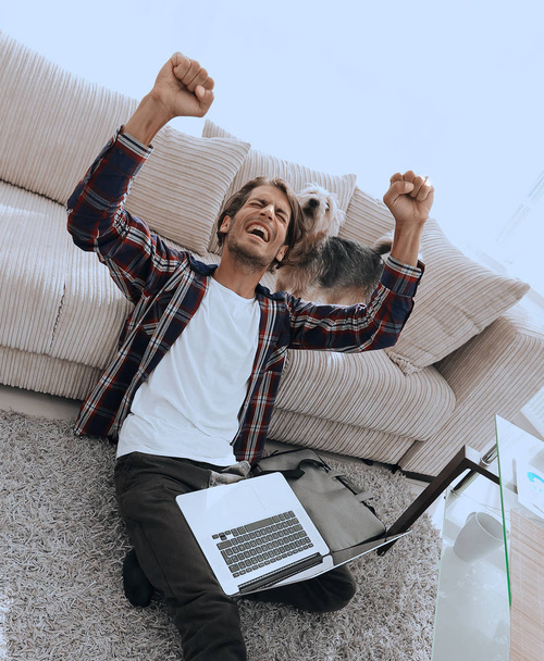 happy guy with laptop jubilant in spacious living room. - Valokuva, kuva