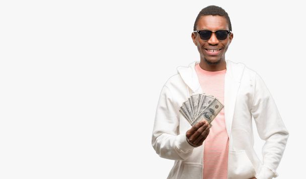 Африканських чоловік тримає долар банкнот, впевненою і щаслива з великий усмішкою природні сміятися - Фото, зображення