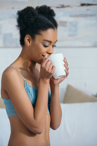 happy african american girl drinking coffee in bedroom in morning  - Photo, Image