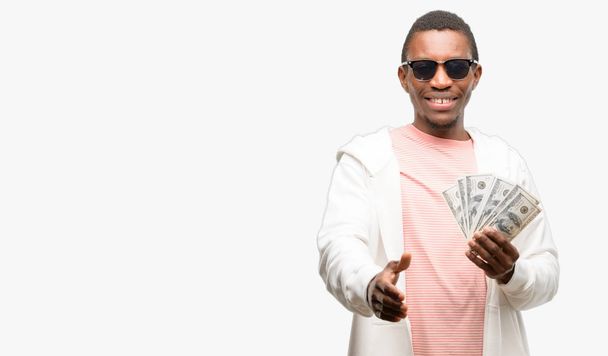 Африканський чоловік тримає долар банкнот тримає руки вітаючи в рукостискання позі, висловлюючи довіру і успіх концепції, привітання - Фото, зображення