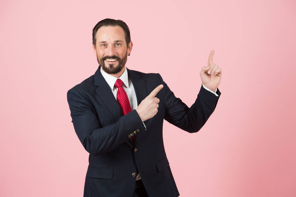 Manager pointing up by fingers on pink background. Man in suit advertise place by hands. Officer points to space for advert - Φωτογραφία, εικόνα