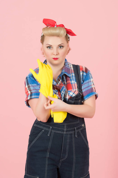 Take latex gloves on hand! Blonde young housewife taking on yellow latex gloves before cleaning. Pin-up modern style concept - Foto, Imagem