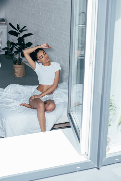 attractive young woman sitting on bed in morning at home - Fotografie, Obrázek