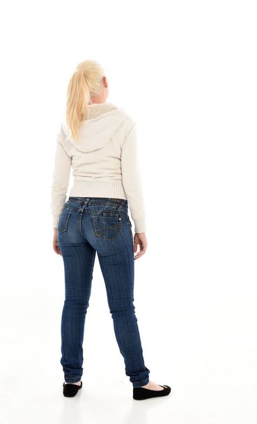 портрет блондинки в білому светрі і джинсах. стояча поза на білому фоні студії
 - Фото, зображення