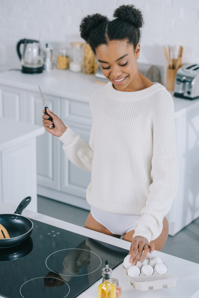 bela jovem mulher tomando ovo da caixa para preparar o café da manhã na cozinha
 - Foto, Imagem