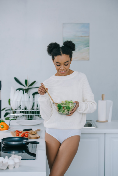 beautiful young woman with bowl of healthy salad at kitchen - Photo, Image