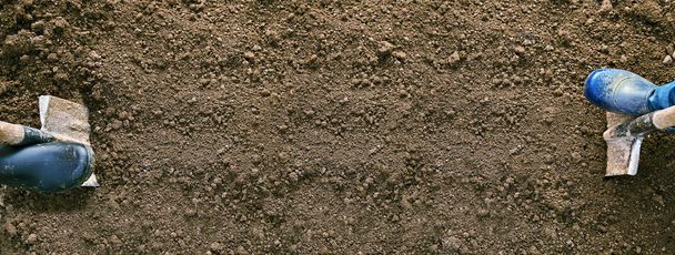 Concept de travail de jardin avec un espace de copie. Pieds mâles et femelles en chaussures en caoutchouc creusant le sol avec des pelles sur les bords d'une longue bande de terre creusée
. - Photo, image