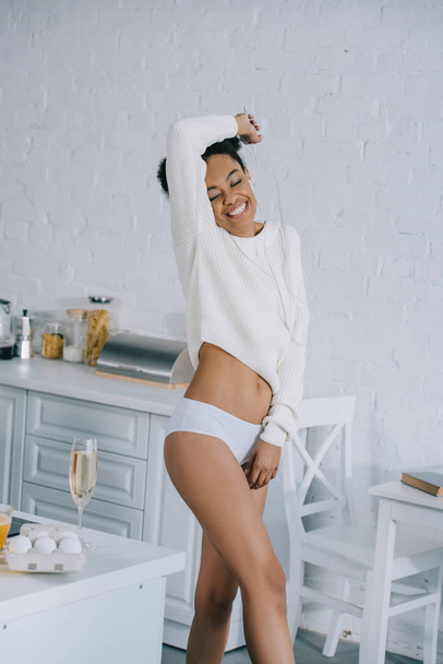happy young woman in underwear and sweater dancing at kitchen - Photo, Image